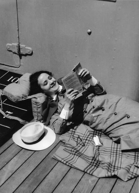 An army nurse reads in comfort aboard a ship. Picture: Australian War Memorial