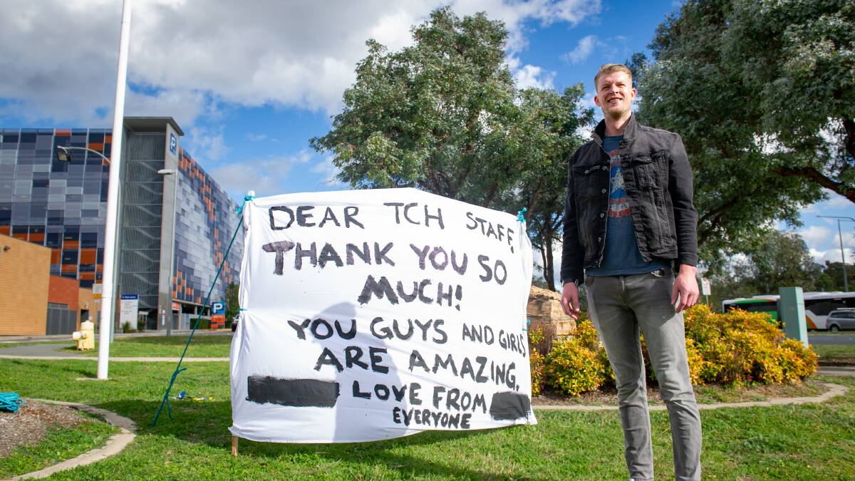 Lanyon High School teacher Cameron Steer, with a sign of thanks he's made for all healthcare workers in the time of coronavirus. Picture: Elesa Kurtz