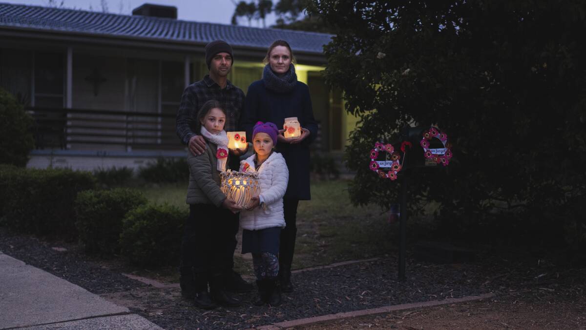 Gavin and Tanya Dunley, with daughters Olivia and Laila, mark Anzac Day in the driveway of their Kambah home on Saturday morning. Picture: Dion Georgopoulos