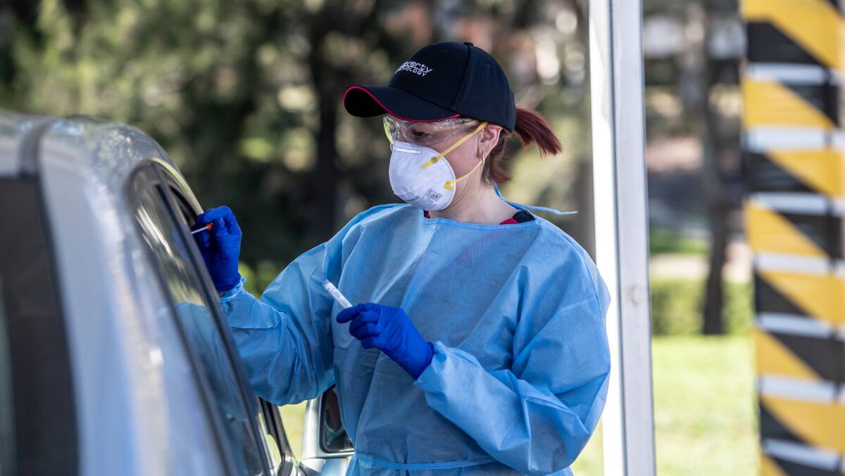Laverty pathology area co-ordinator Ann Deniz testing people for coronavirus at the Weston Creek drive-through centre while wearing personal protective equipment. Picture: Karleen Minney