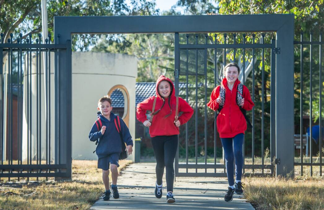 Having already returned to school earlier Cooper Cunanan, year three, now has his big sister Jayda Cunanan and her friend Lucy Downes, both in year five, back at Gilmore Primary School with him. Picture: Karleen Minney