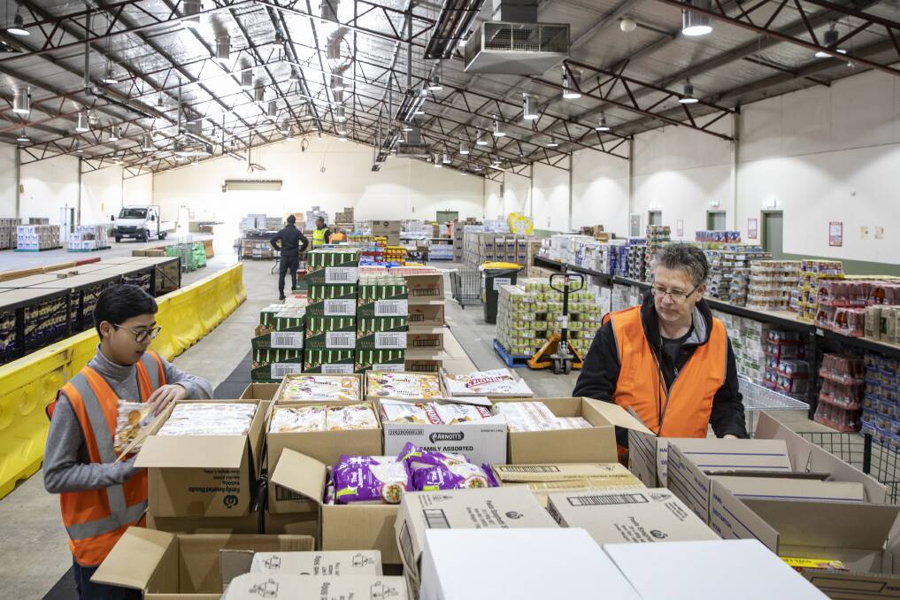 Volunteers Kazimier Lim and Martin Scott at the Canberra Relief Network warehouse. Picture: Sitthixay Ditthavong