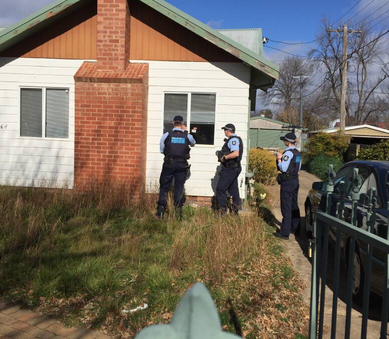 A person in self-isolation in Canberra shows identification through the front window to police officers conducting a spot check. Picture: Peter Brewer 