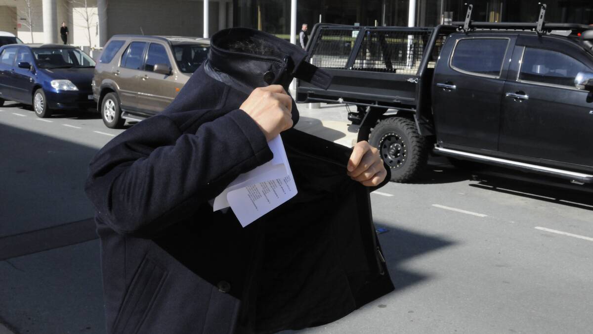 Kenny Choi tries to hide as he leaves the ACT Magistrates Court on Tuesday after being granted bail. Picture: Blake Foden