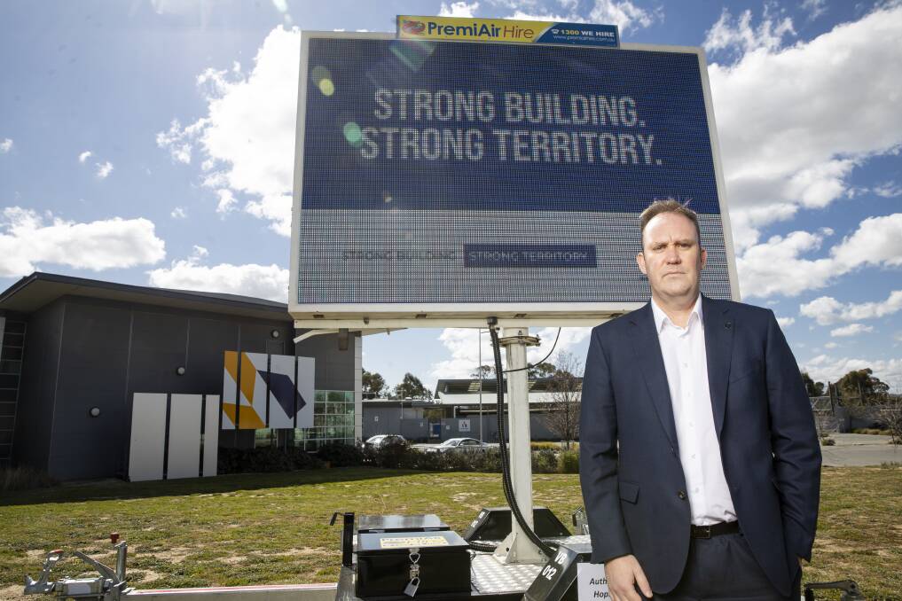 Master Builders ACT chief executive Michael Hopkins at the front of an election billboard at the association's Fyshwick offices. Picture: Sitthixay Ditthavong
