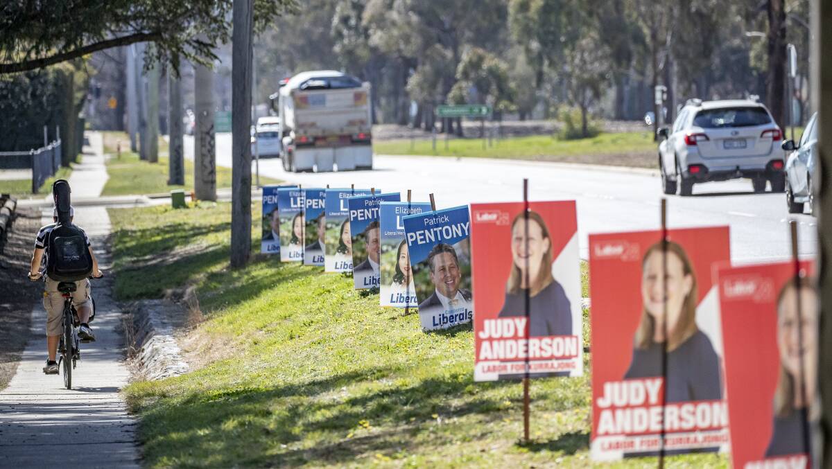 A cyclist rides past corflutes promoting candidates for the ACT election on Limestone Avenue this week. Picture: Sitthixay Ditthavong