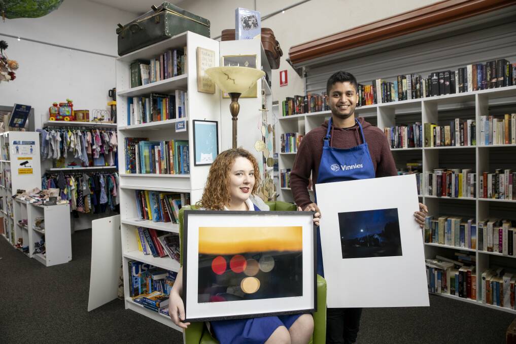 Vinnies Dickson staff Heather Freckelton and Hammad Naqvi with some of the prints donated by photographer Sean Davey. Picture: Sitthixay Ditthavong