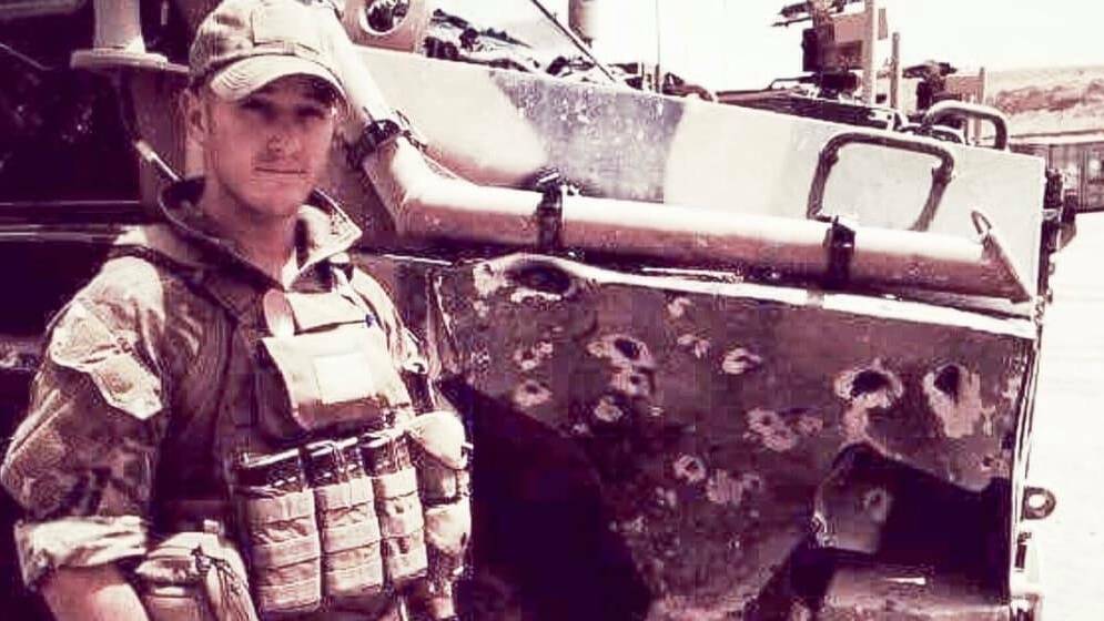 Portrait of Trooper David Nicolson standing beside IED damaged vehicle in Afghanistan. Picture: David Nicolson