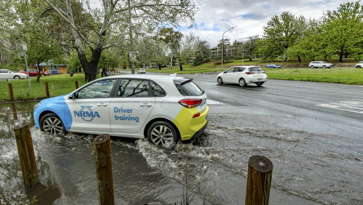A motorist navigates the flooded entrance to the Bowen Park car park. Picture: Sitthixay Ditthavong