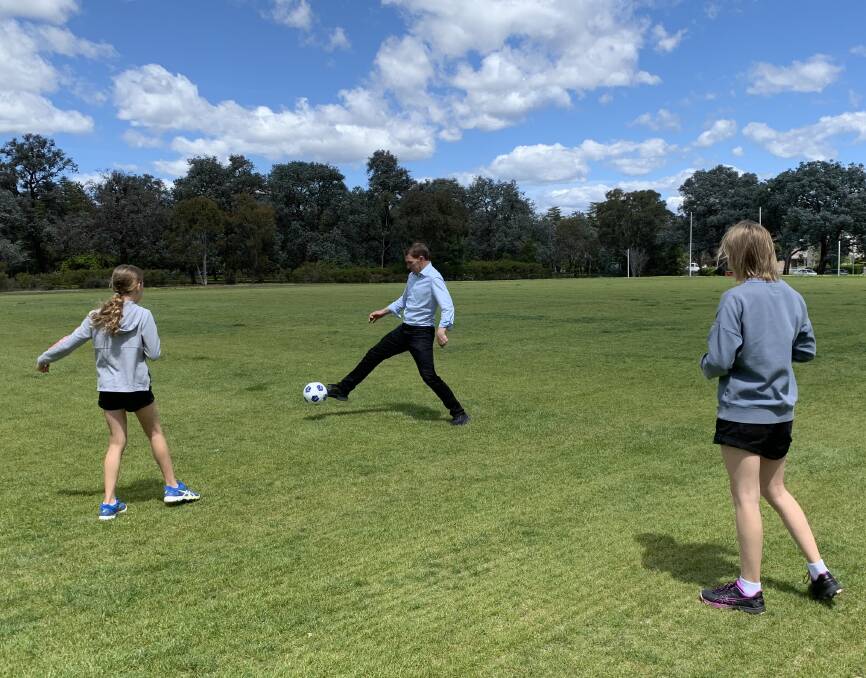 Liberal leader Alistair Coe kicks a soccer ball with sisters Lucy and Ava Morris. Picture: Peter Brewer