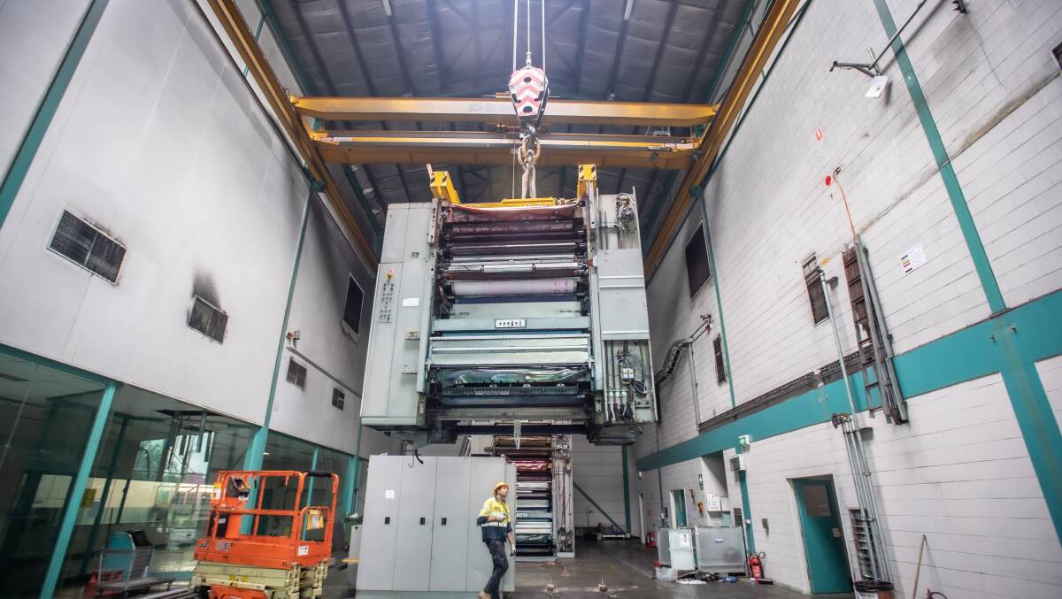 A 40-tonne section of the Canberra Times printing press is dismantled and lifted by crane. Picture: Karleen Minney