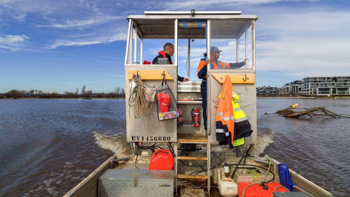 Works Manager Tony Le Mesurier and operator Jeff Koehler motor past a dead tree floating in Lake Burley Griffin's east basin. Picture: Sitthixay Ditthavong