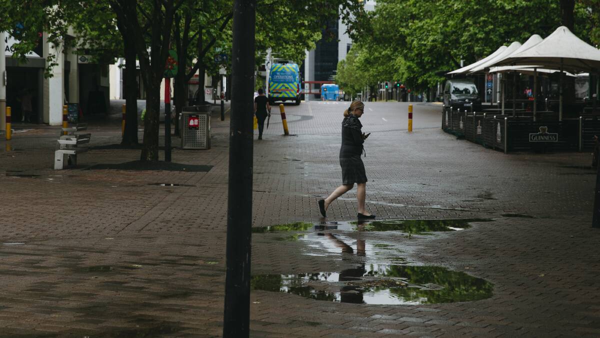 People walk through Garema Place in Civic after heavy rainfall. Picture: Dion Georgopoulos