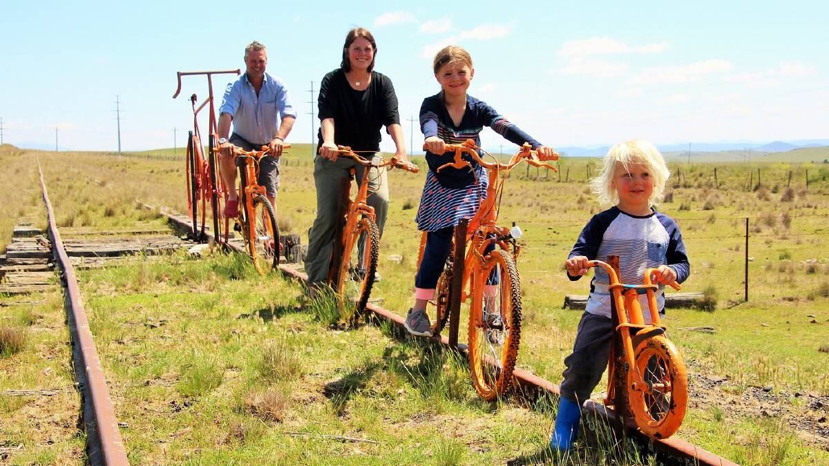 Nimmitabel residents Will and Caroline Jardine with their children, riding the orange bikes which line the track to show support for the rail trail. Picture: David Moore