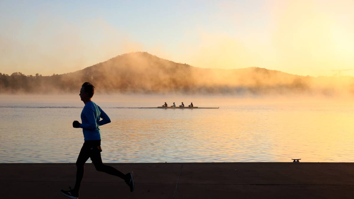 A jogger braves the cold morning on Lake Burley Griffin this week, as a cold front moves across the ACT. Picture: James Croucher