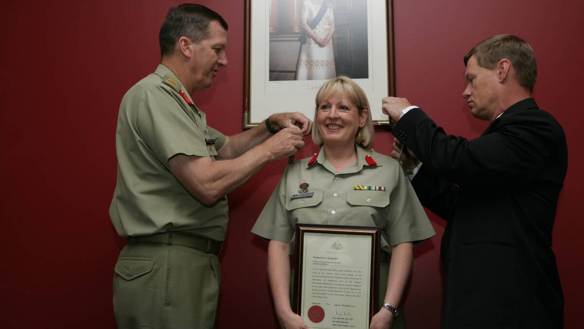 In 2005 Liz Cosson was the first woman in the Army promoted to Brigadier. Then chief of Army Peter Leahy and her partner James Baker, pictired, placing her rank slides. Picture Department of Defence
