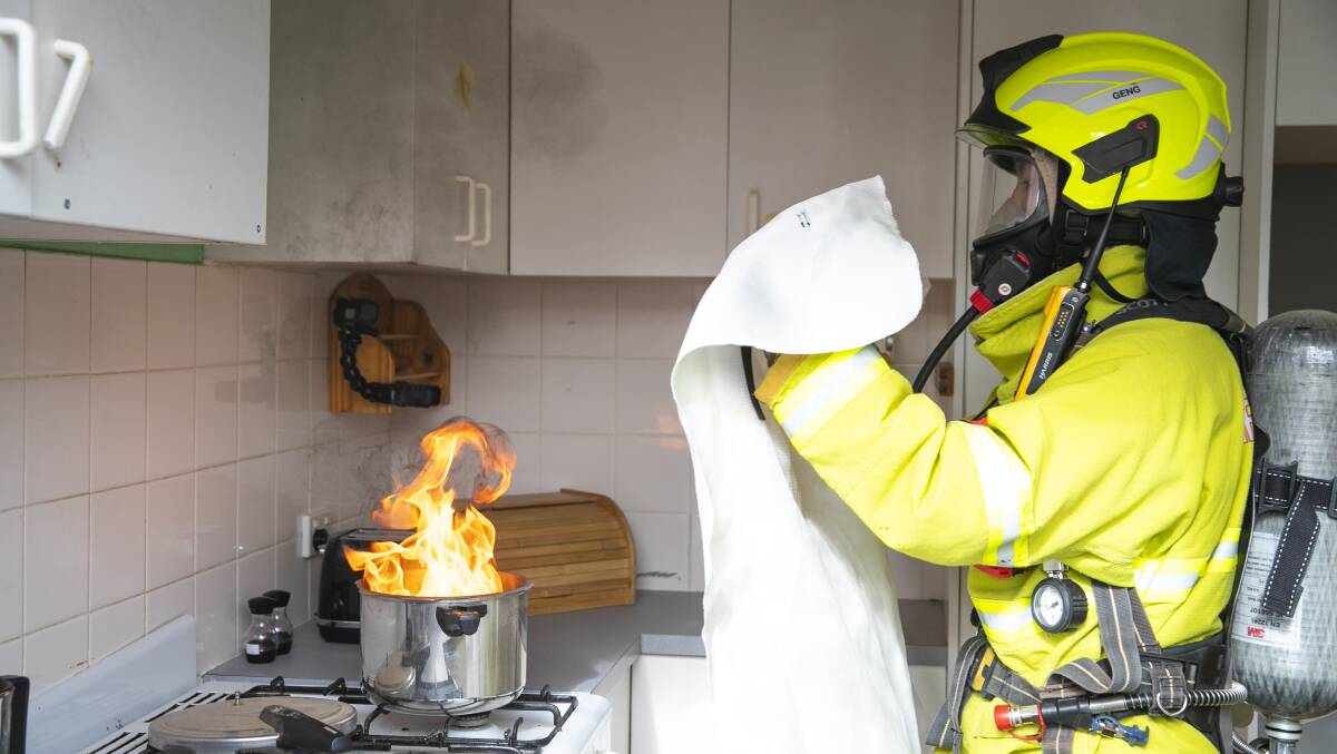 Firefighter Martin Geng demonstrates how to extinguish a fire on a stovetop. Picture: Keegan Carroll