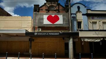 A bright red heart banner attched to the second story of the boarded up Newcastle Permanent buliding in Lismore. Picture: Marina Neil