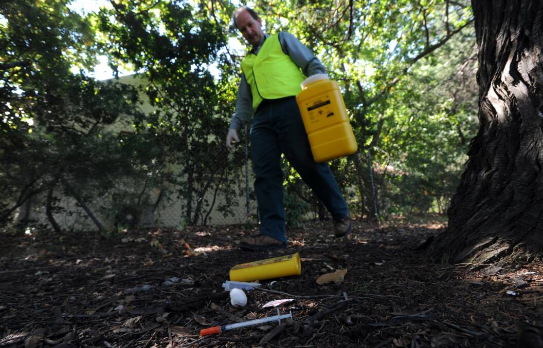 A city ranger collects a discarded syringe in Canberra. Picture by Graham Tidy