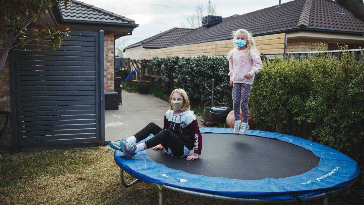 Sisters Amelia, 10, and Josie Tozer, 6, playing on their trampoline, at their home in Queanbeyan during the 2021 COVID-19 lockdown. Picture: Dion Georgopoulos