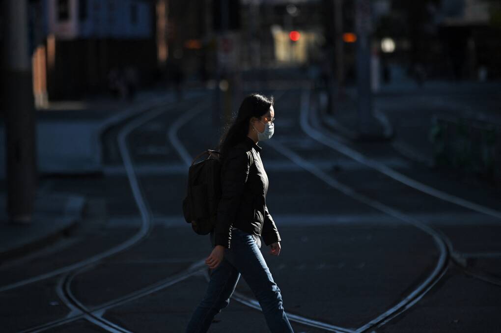 A woman wearing a mask crosses tram tracks in the empty central business district in Sydney on Sunday on the first full day of a two-week COVID-19 coronavirus lockdown. Picture: Getty Images