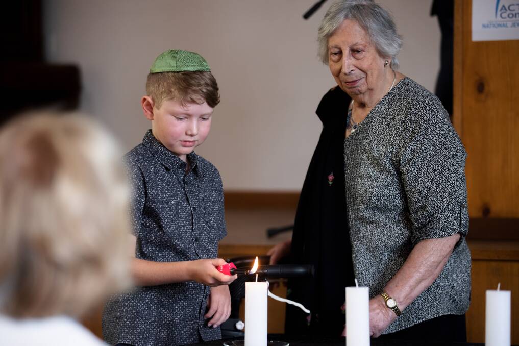 Adam Hoffman lights a candle with Holocaust survivor Ruth Landau at the National Jewish Memorial Centre on Wednesday to mark International Holocaust Remembrance Day. Picture: Sitthixay Ditthavong