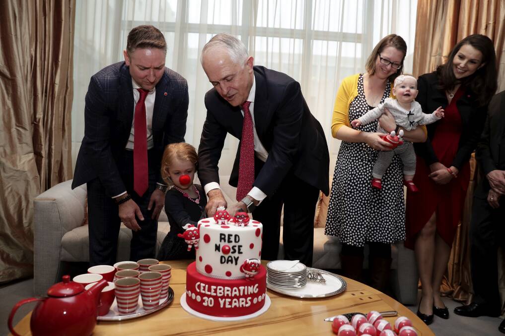 Red Nose board chair Craig Heatley, three-year-old Isobel Carroll and Prime Minister Malcolm Turnbull cut the cake celebrating 30 years of Red Nose Day. Photo: Alex Ellinghausen
