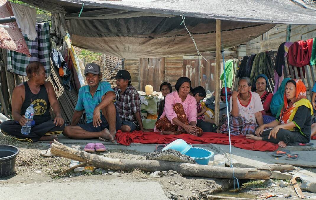 Sangati, far right, and neighbours sit under a tarpaulin that will serves as shelter also at night. Photo: Amilia Rosa