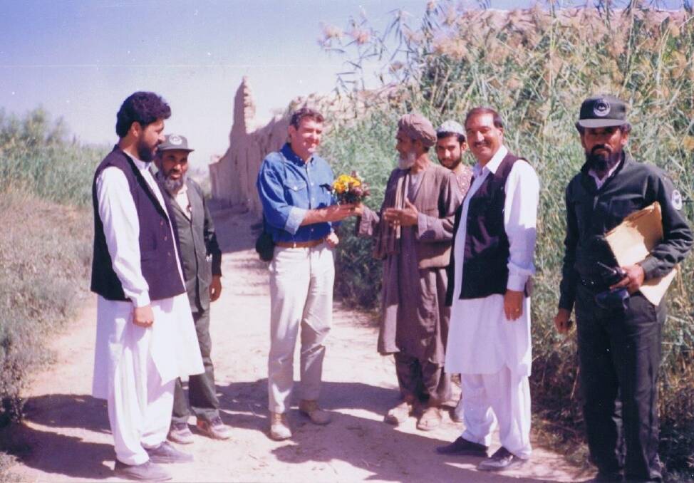 Making a difference: Ian Mansfield, third from left, is presented with a bunch of flowers by an Afghan man near Kandahar in the early 1990s. The man was grateful for the work done to demine his land. "It is one of the best gifts I have ever received," Mansfield said. Photo: Supplied