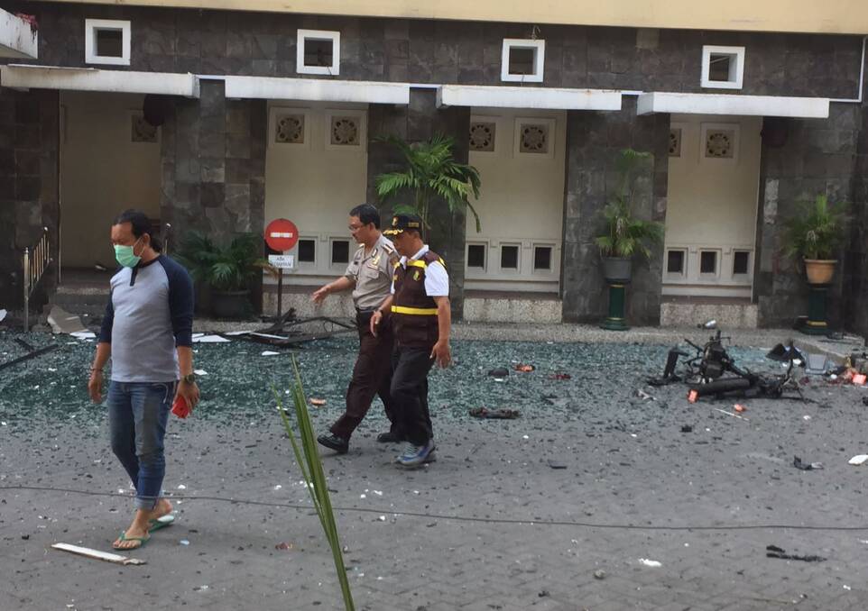 Officers walk past debris at Santa Maria church in Surabaya.  Photo: AP