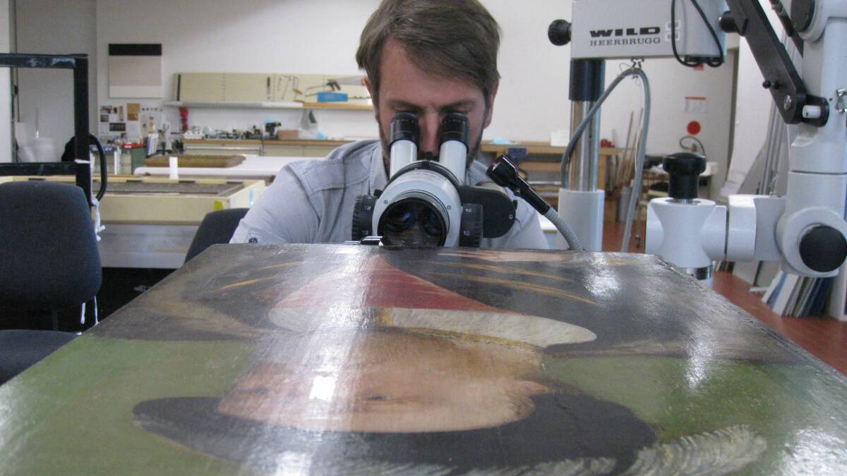 ANU academic Dr Matthew Brookhouse examining the portrait of Henry VIII. Photo: Simon Ives