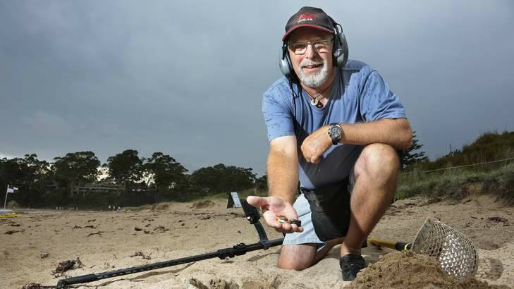Surf Beach local Bevan Badcott using a metal detector at Surf Beach, Bevan runs a business helping people find lost jewellery and also helps remove any metal waste he finds on the beach. Photo: Jeffrey Chan