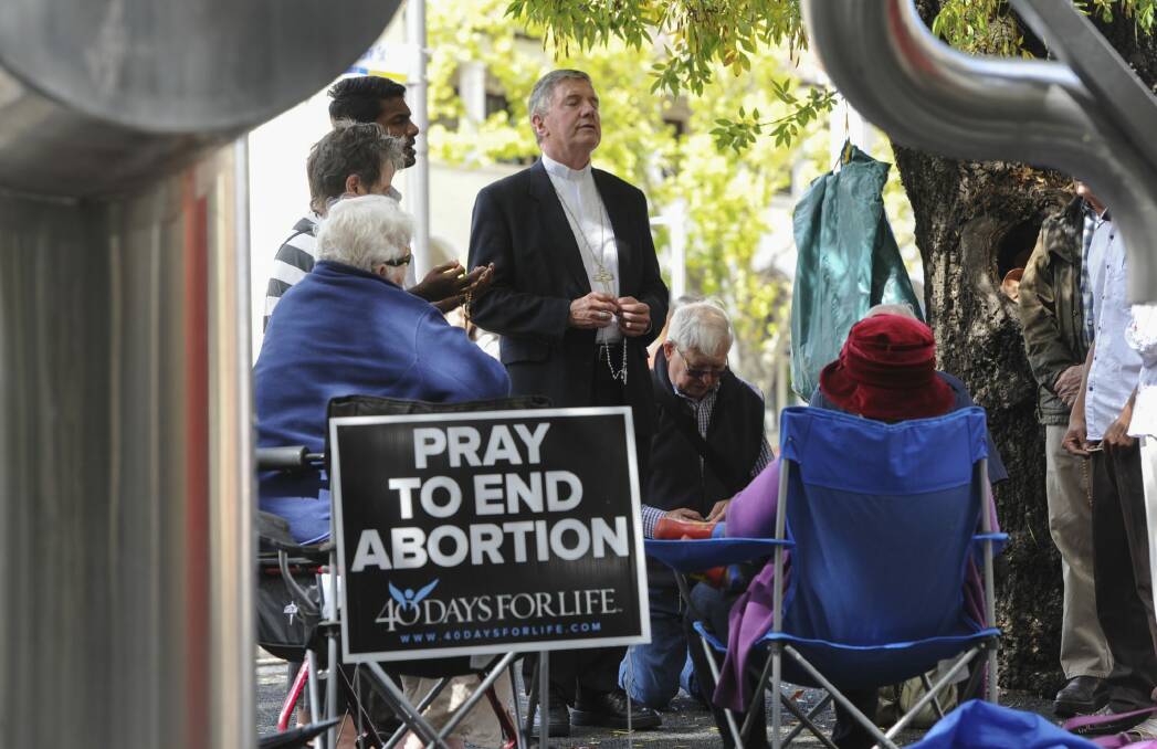 Catholic Archbishop of Canberra and Goulburn Christopher Prowse, centre, attends a prayer vigil outside the Moore Street abortion clinic in March. Photo: Graham Tidy