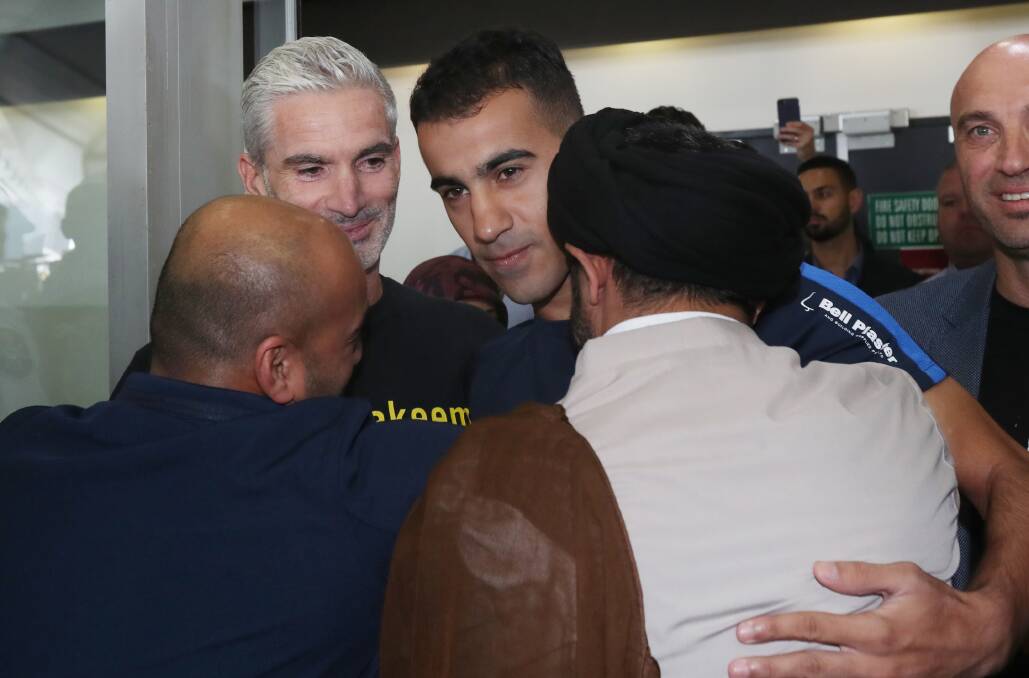 Former Socceroo Craig Foster (left) is seen with refugee footballer Hakeem Al-Araibi (centre) as he is greeted by supporters upon arriving at Melbourne International Airport in Melbourne, Tuesday, February 12, 2019. Photo: AAP