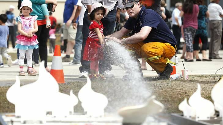 Jerrabomberra Brigade member Tim Heseltine shows Situmi Maddumage, 3, of Dickson, how to use a fire hose. Photo: Jeffrey Chan