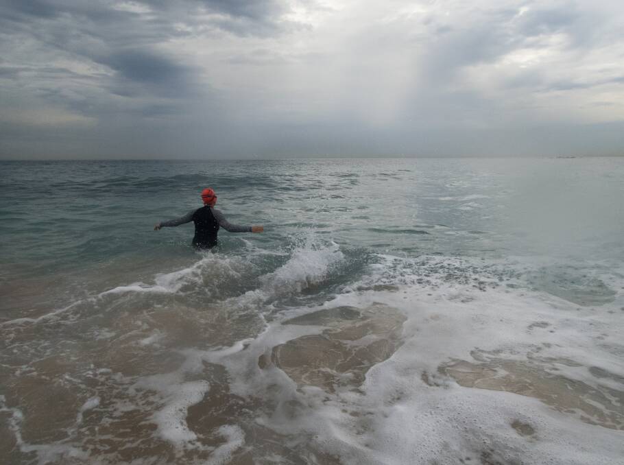 A swimmer at Coogee as storm clouds hover. Photo: Janie Barrett