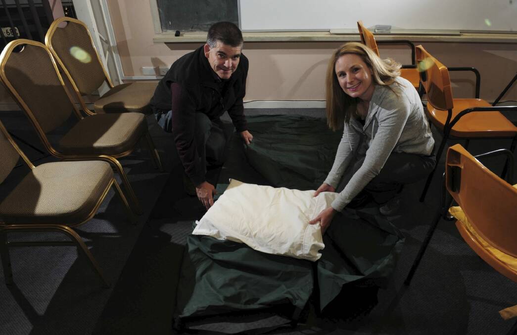 Volunteers Geoff Wellington of Pearce, and Naomi Cole of Lyneham, make up a bed at the Safe Shelter for homeless men at the St Columba's Uniting Church hall in Braddon Photo: Graham Tidy