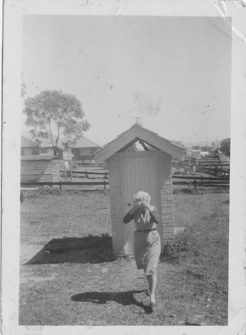 A woman leaving a Coopers Plains dunny, nursing a headache.