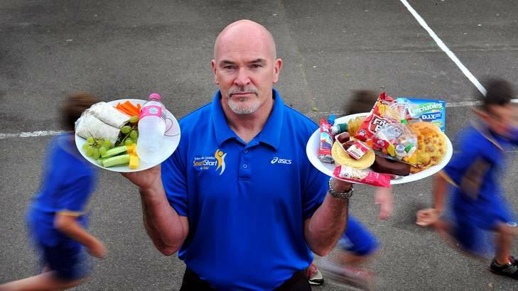 Rob de Castella stands in the Giralang Primary school yard and display's in his left hand a plate of healthy affordable food and his right  unhealthy and quite expensive food. Photo: Colleen Petch