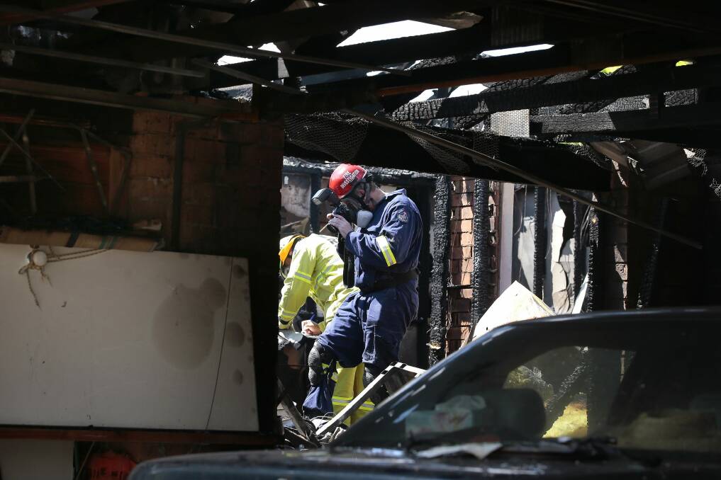 Investigators examine a house fire at Chapman on Friday morning.  Photo: Jeffrey Chan