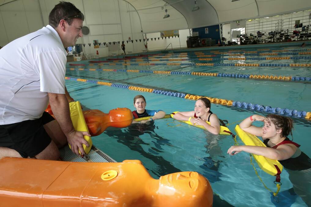 Royal Life Saving ACT training manager Ben Cuttriss instruct Calwell High School students Kirralee- Rose Schofield, year 10, Nia Cavanagh, year 7, and Lauren Smith, year 10, on the manikin tow during the school's swimming carnival at the Canberra Olympic Pool. Photo: Jeffrey Chan
