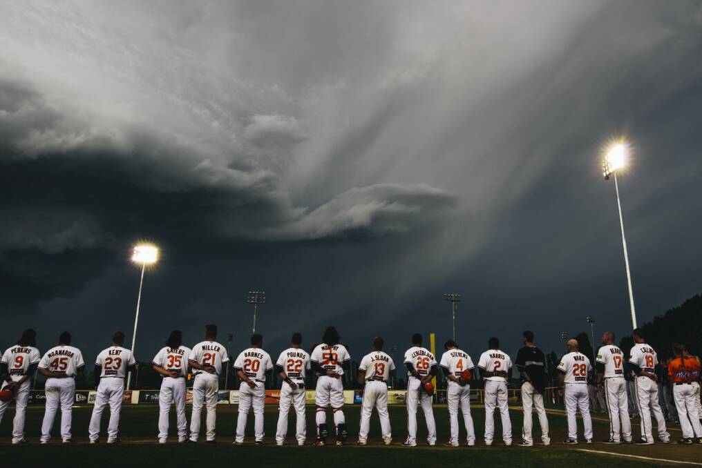 Canberra Cavalry players line up during a moment of respite from the supercell storm in Canberra on Saturday. Photo: Rohan Thomson