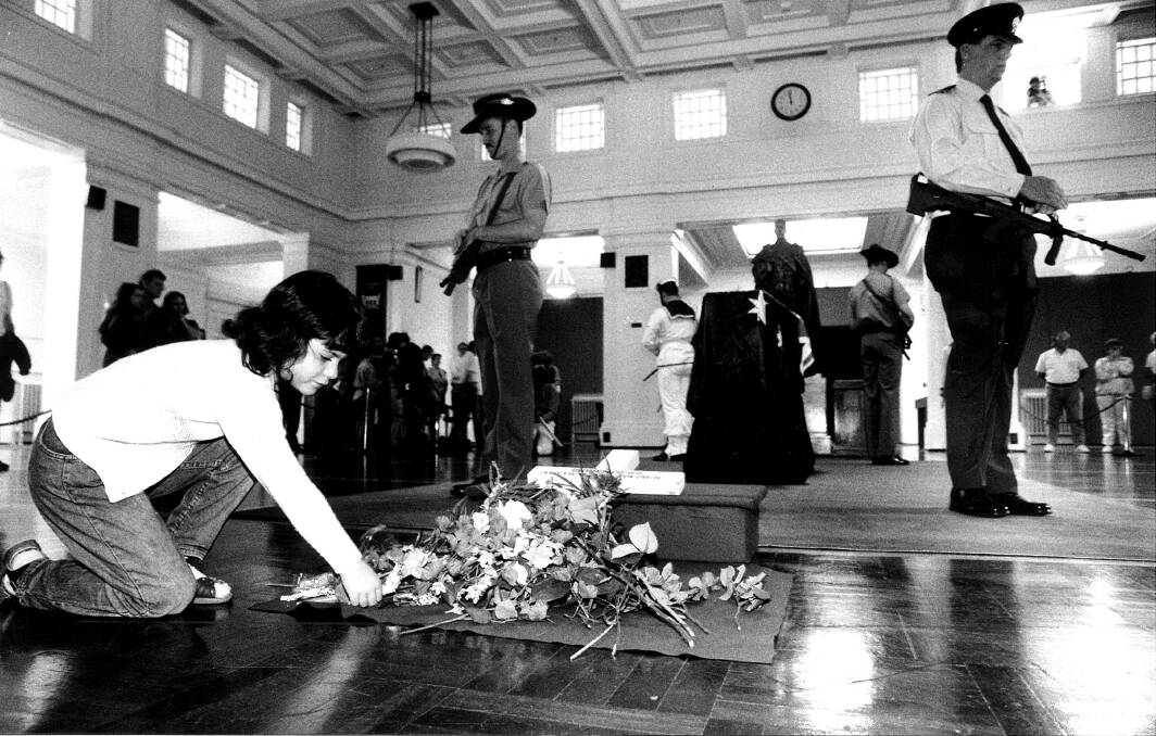 Zoe Sander lays a flower at the coffin of the unknown soldier in Kings Hall at Old Parliament House. Photo: Gary Schafer