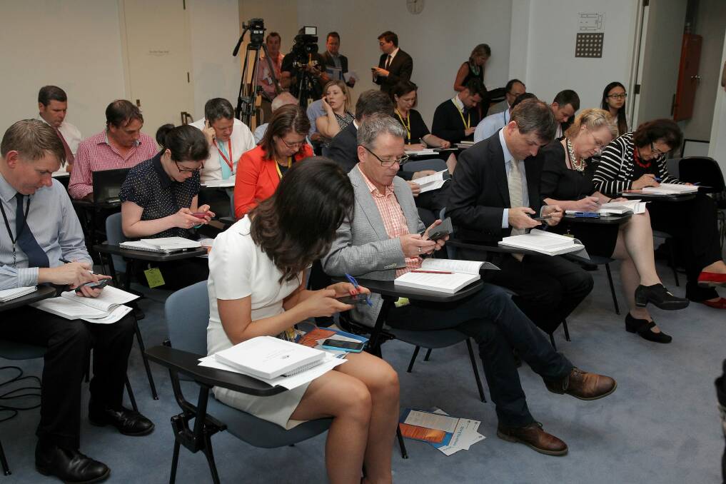 Journalists read their copies of the MYEFO ahead of the update from the government. Photo: Alex Ellinghausen