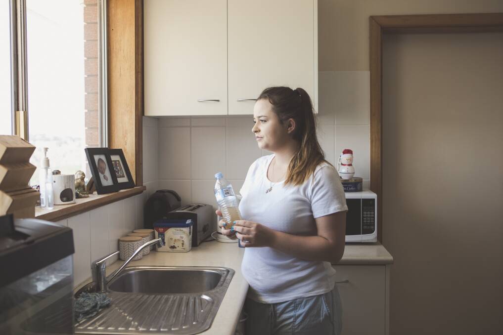 Yass resident Anastasia Stephenson with the brown water she poured from her kitchen tap last week. Photo: Jamila Toderas