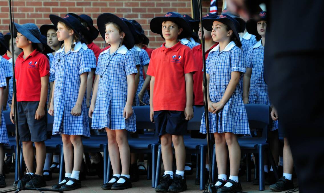 The French President, Francois Hollande, visits the French Australian School, Telopea Park. Students sing the French national anthem upon the arrival of the president. Checking out the president during the song is 8 year old Armand Bouillaud, centre.  Photo: Graham Tidy