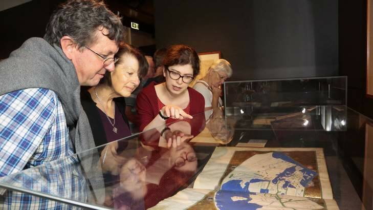 Duncan McLay and Neryl McLay from the Gold Coast are show a world map in Geographia by Claudius Ptolemy by Mapping the World co-curator Susannah Helman. Photo: Jeffrey Chan