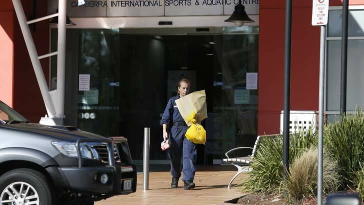 A forensic investigator carries items from the Canberra International Sports and Aquatics Centre in Belconnen after the incident. Photo: Jeffrey Chan