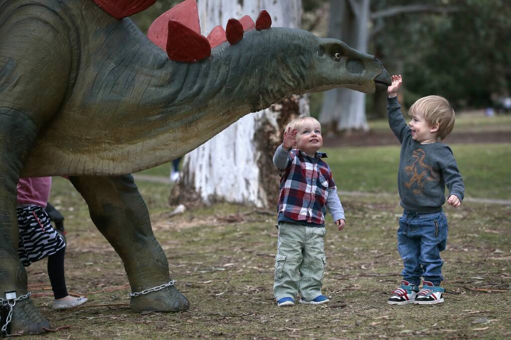 Eli Wilson, 2, and Arlo McClinton, 2, both of Downer, befriend a stegosaurus on the Prehistoric Discovery Trail. Photo: Jeffrey Chan