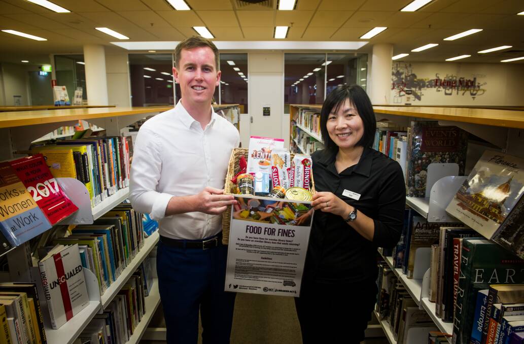 City Services Minister Chris Steel with l library service officer, Yumi Ezaki, at Civic Library to launch the Food for Fines program. Photo: Elesa Kurtz
